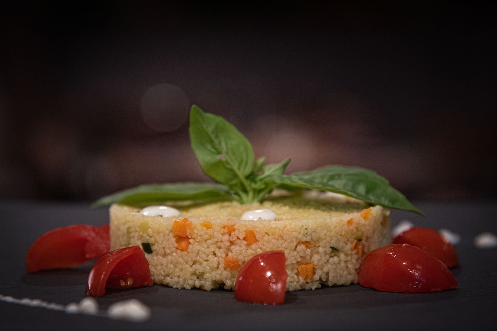 Gourmet couscous dish garnished with fresh basil and cherry tomatoes, perfect for meals.